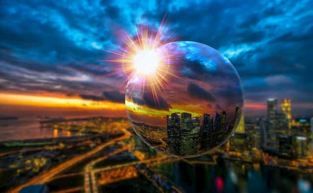 Sun shining through glass ball & city background Shifting Our Perspective