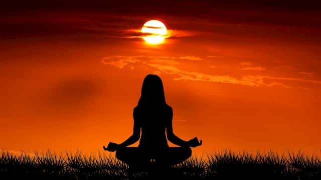 Woman meditating at Sunrise centered in Divine Beingness