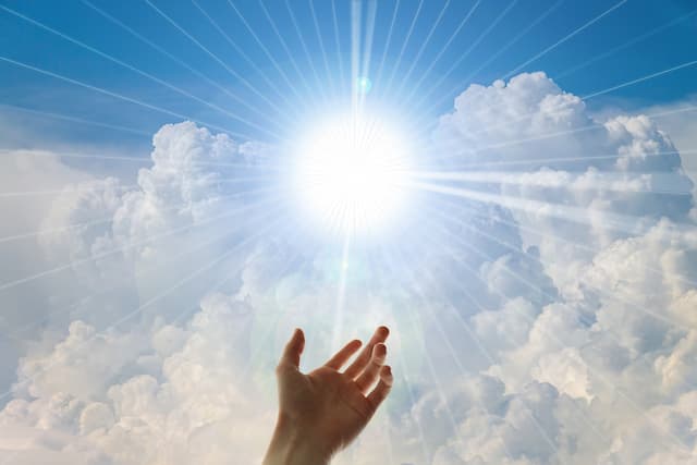Divine Guidance at Hand - Sun shining through clouds toward uplifted hand